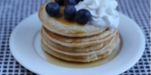 Pancakes on a plate with blueberries and cream