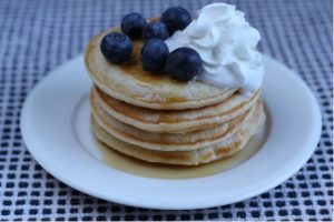 Pancakes on a plate with blueberries and cream