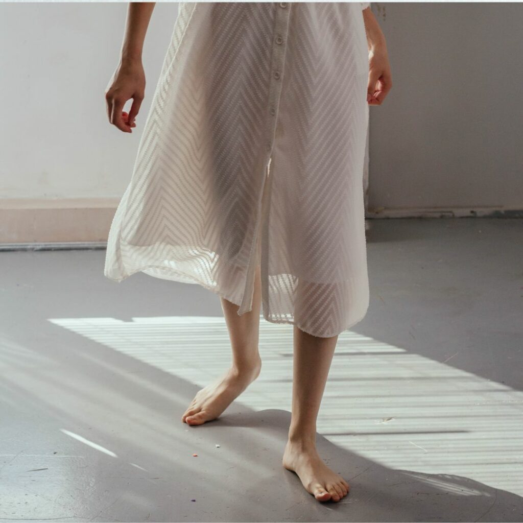 Lady walking with bare feet on a wooden floor.