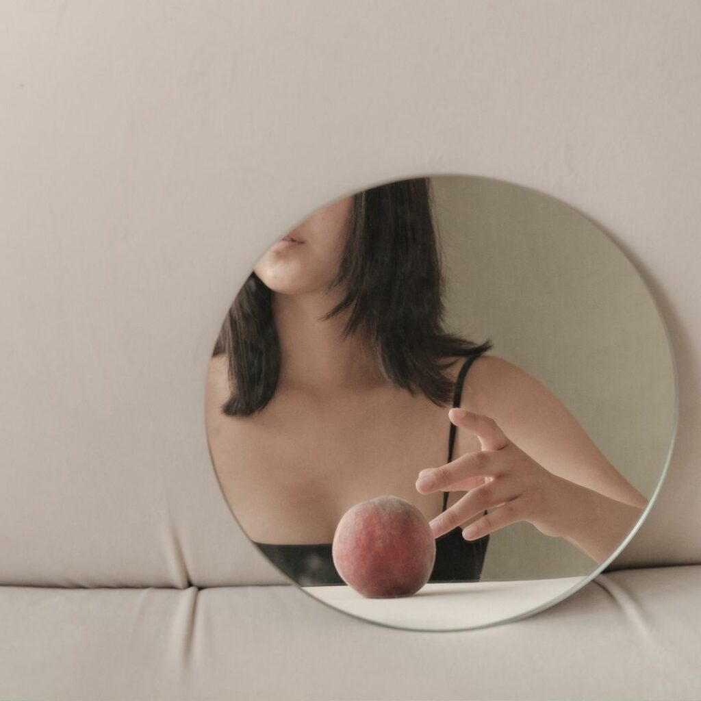 Reflection of lady looking into the mirror touching a peach